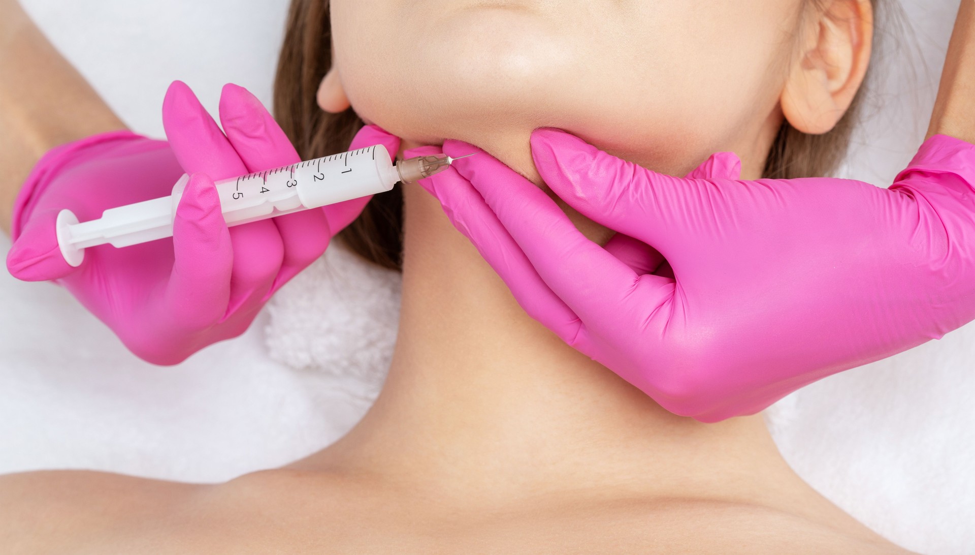 Cosmetologist makes lipolytic injections to burn fat on the chin, cheeks and neck of a woman against double chin. Female aesthetic cosmetology in a beauty salon.Cosmetology concept.