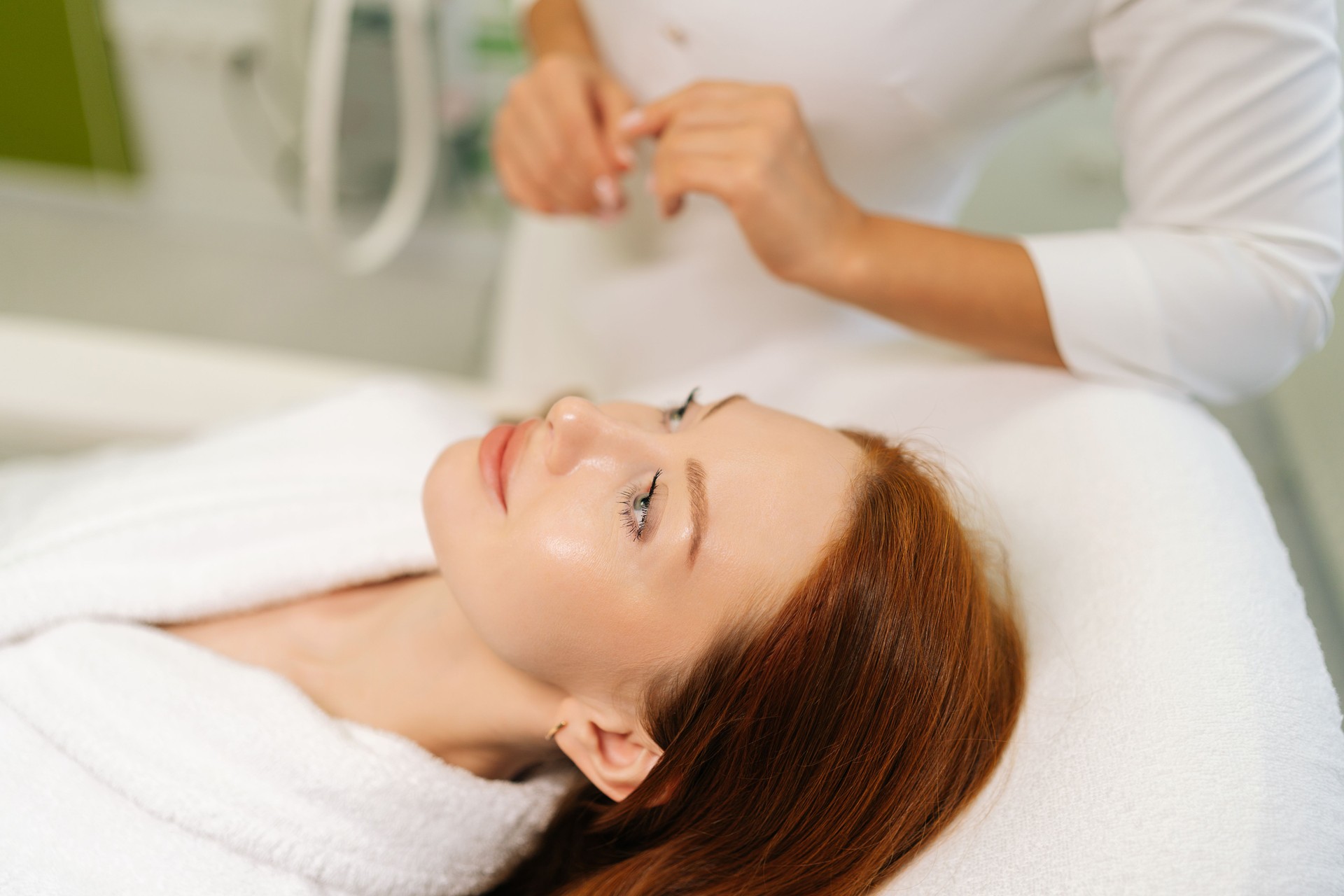 Unrecognizable beautician reassuring female patient before starting beauty or wellness treatment in modern bright clinic, taking care and creating relaxing atmosphere.